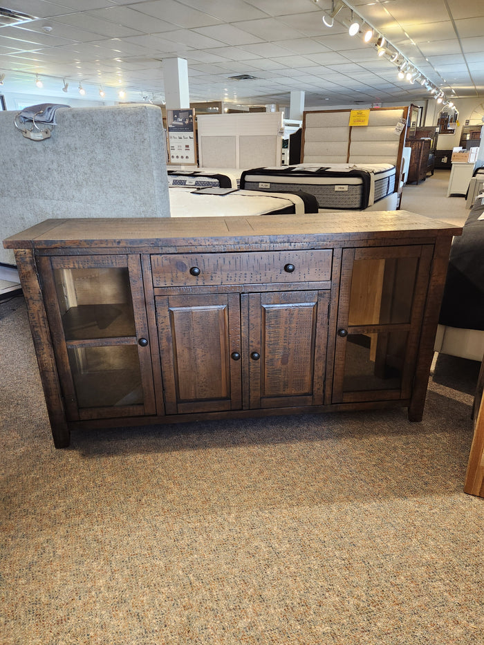 The Jofran Willow Creek Server features glass-paneled doors and adjustable shelves, showcased in a furniture showroom.