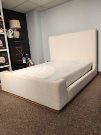 The Fashion Nala Bed, a cream boucle platform with wingback headboard, sits in a carpeted showroom corner.