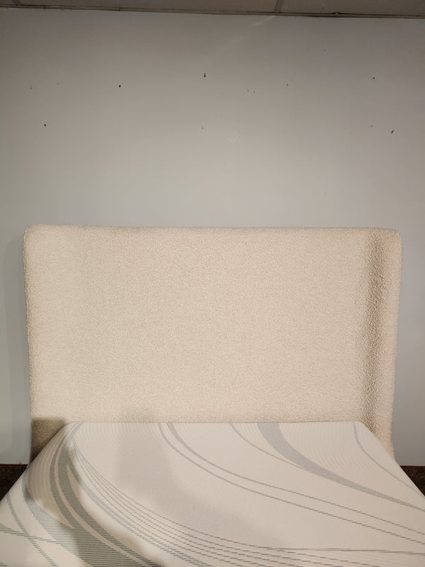 The Nala Bed by Fashion features a cream boucle wingback headboard and mattress with a striped sheet in front.