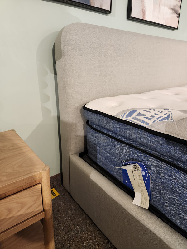 Close-up of a Palliser EQ3 Nara Queen Bedframe with modern headboard, blue mattress, and wood nightstand on carpet.