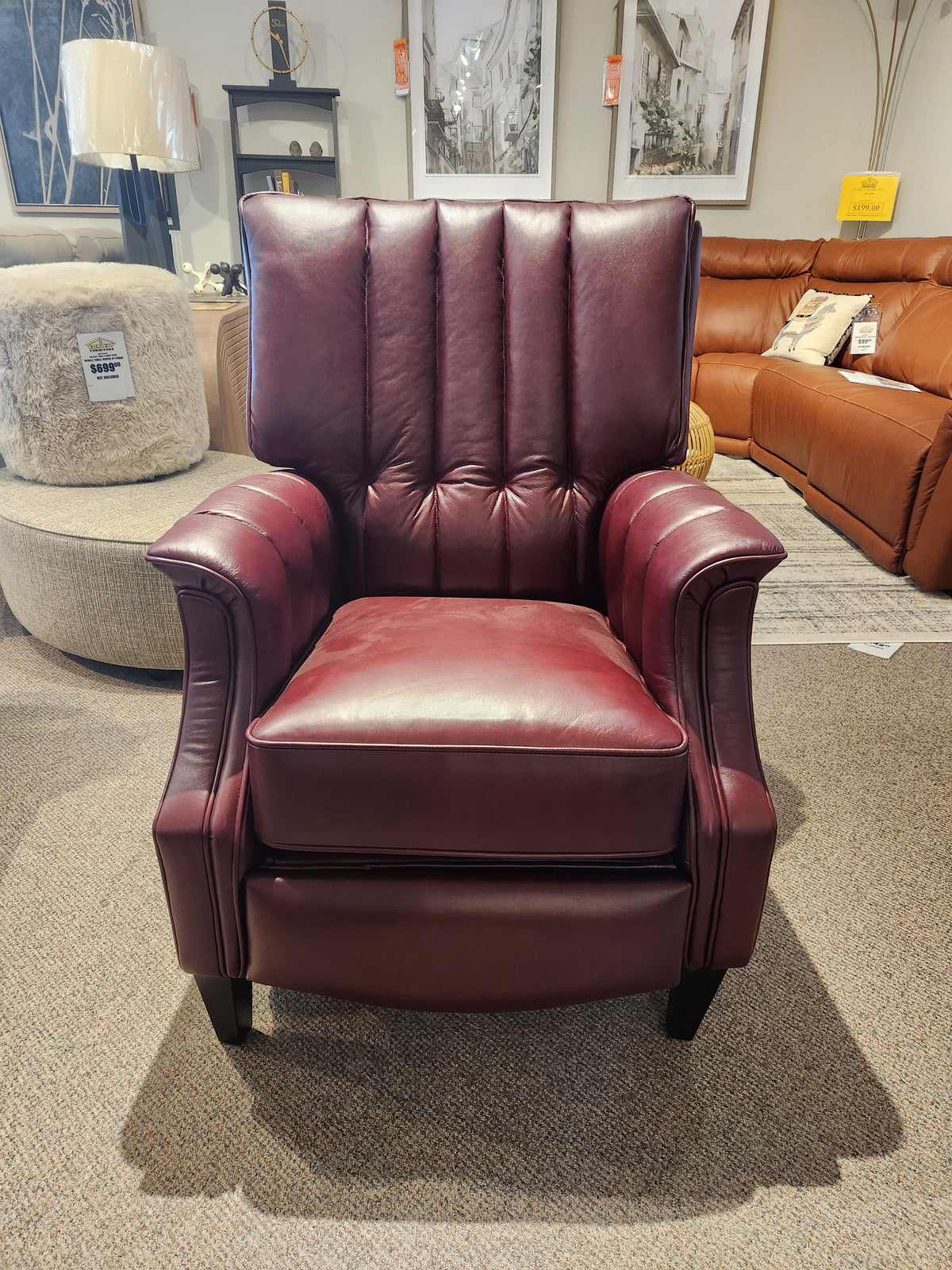 A Leather Craft 686 Reclining Chair in burgundy Canadian leather with vertical tufting is on the showroom floor.