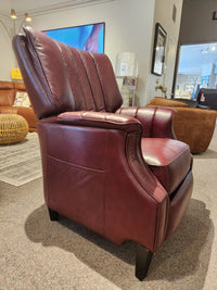 The Leather Craft 686 Reclining Chair is maroon Canadian leather with armrests and dark wooden legs in a showroom.