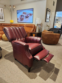 The Leather Craft 686 Reclining Chair in burgundy with extended footrest is displayed in a leather furniture showroom.