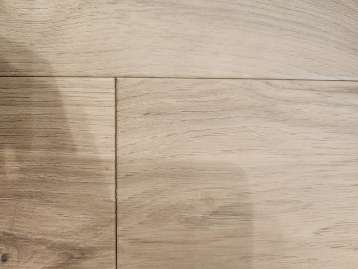 Close-up of BECKHAM BROTHER'S Posh Plank Windsor showing light wood grain and seam between glue down vinyl planks.