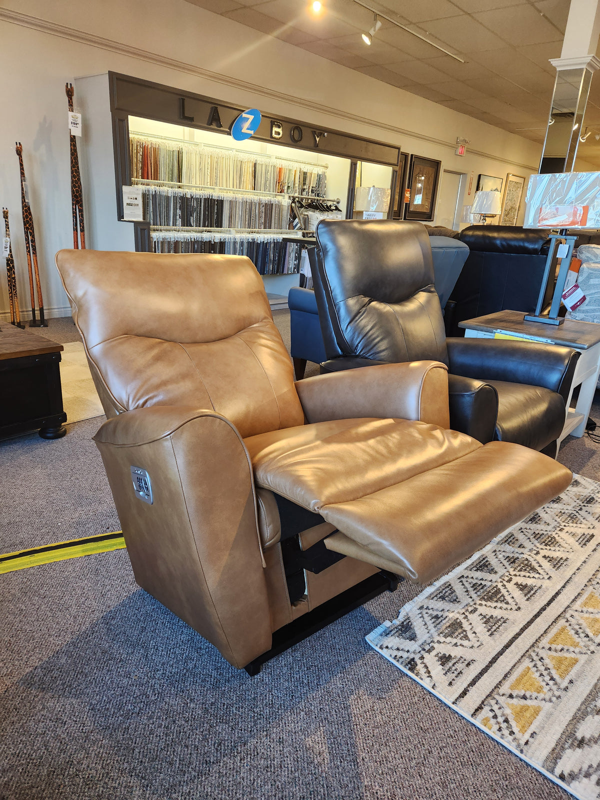 Two La-Z-Boy 804 Belmont Power Rocker Recliners with heat tilt, one tan, one dark brown, in a showroom.