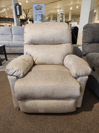 Best 7MP84 Ellisport Power Space Saver Recliner in plush beige on brown carpet, displayed among other showroom furniture.