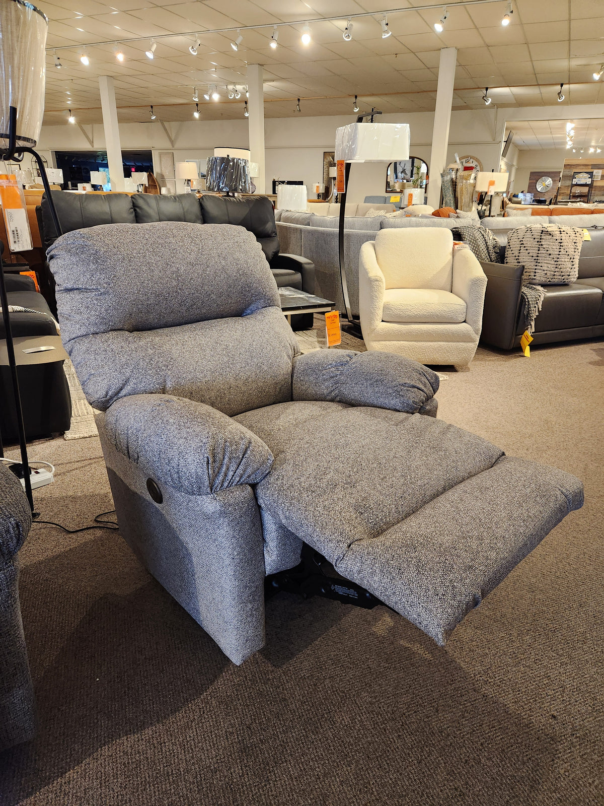 The Best 7MP84 Ellisport Power Space Saver Recliner in gray is displayed among sofas and recliners in a showroom.