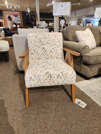 The Bayden 3180 Chair by Best features modern style and wooden sawhorse legs, showcased in a furniture showroom.