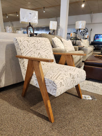 The Bayden 3180 Chair by Best features patterned upholstery and wooden sawhorse legs, shown in a furniture showroom.