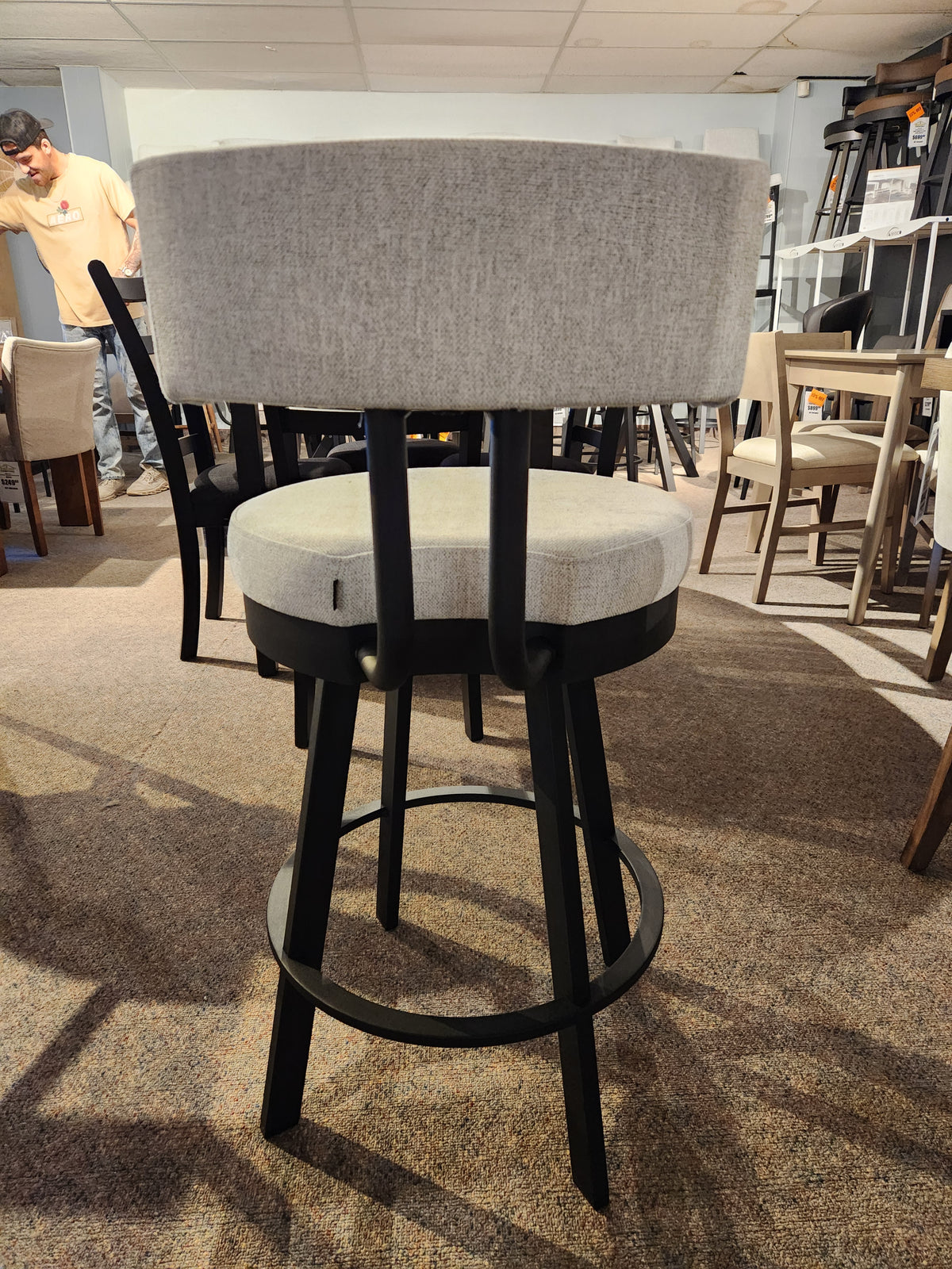 Barry Swivel Bar Stool by Amisco: gray cushion, black steel legs, scratch-resistant finish, shown with other chairs.