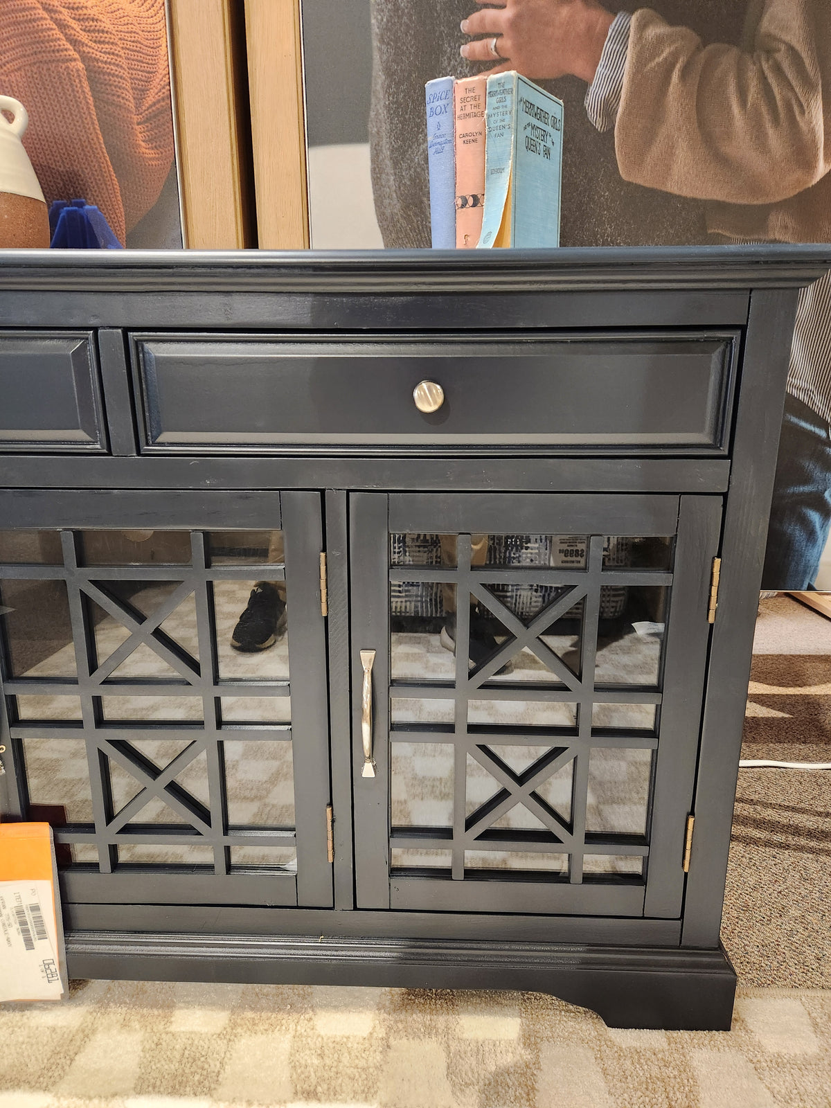 The Jofran 775 Craftsman Console, a black cabinet with mirrored doors, stands on a patterned carpet with reflections.