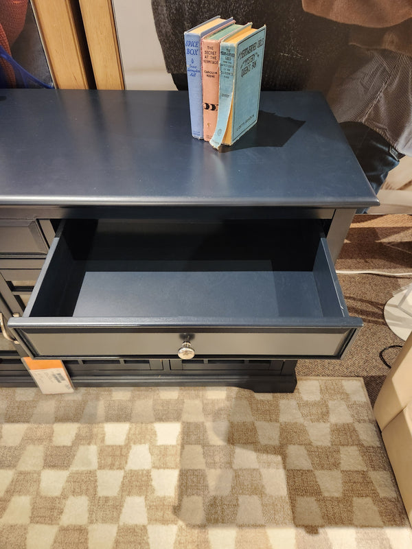 The Jofran 775 Craftsman Console in navy blue features antique hardware, an open drawer, and books on top.