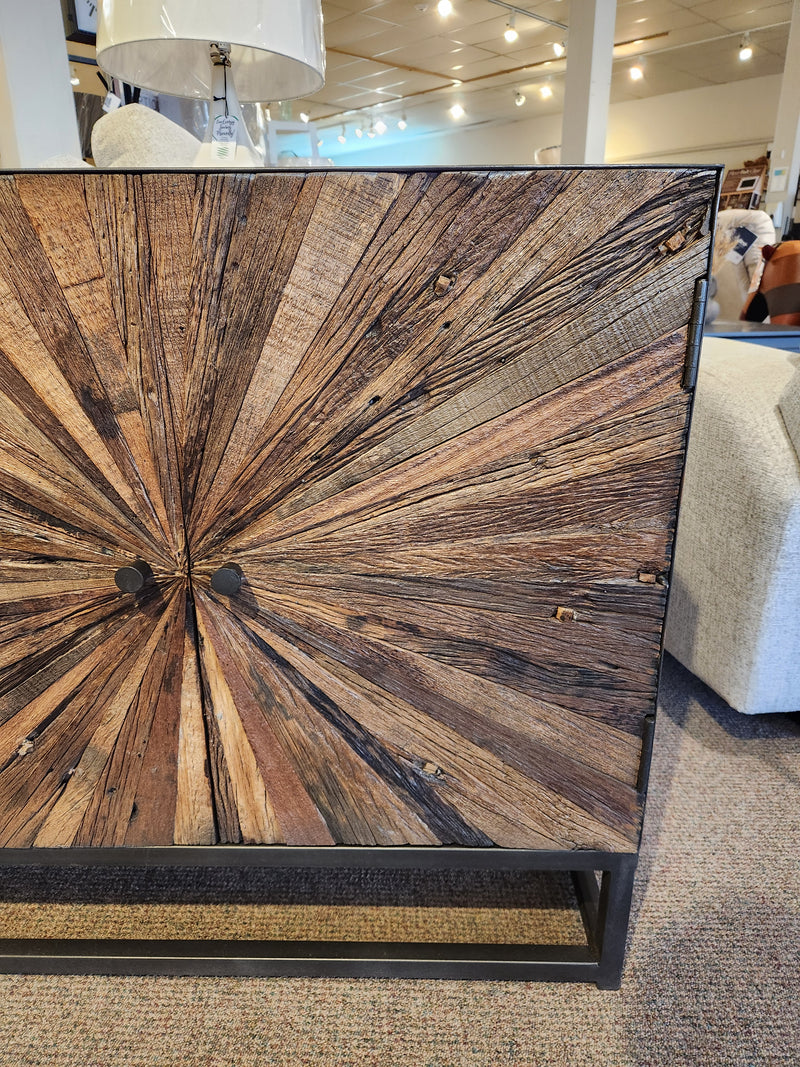 The Jofran 1928 Astral Plains 2 Door Cabinet features a starburst design, shown in a neutral furniture showroom.