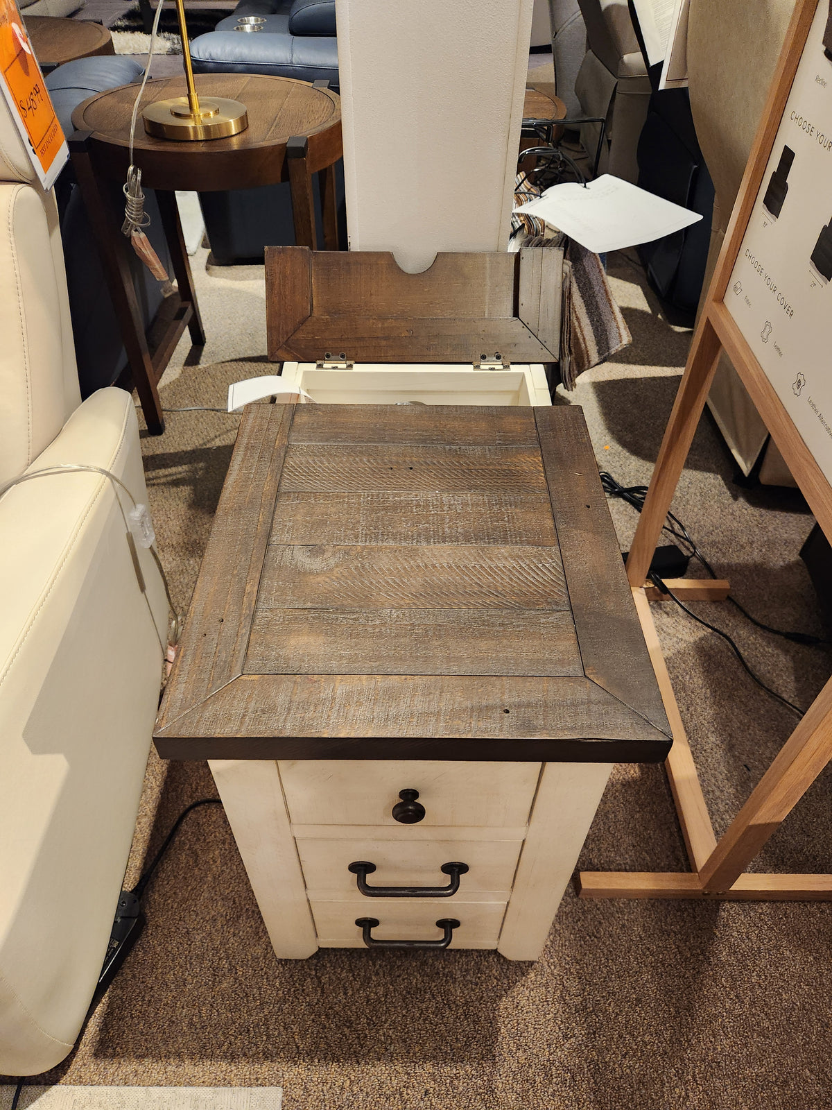 The Jofran 1706 Madison County Power Chairside End Table with barn door accents is displayed in a store.