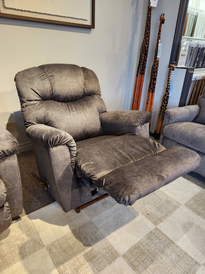 A gray La-Z-Boy 515 Lancer Rocker Recliner with footrest extended sits on a checkered rug in a showroom.