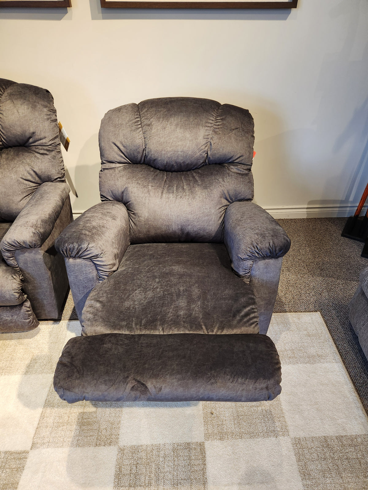 A La-z-boy 515 Lancer Rocker Recliner in gray with matching footrest sits on a patterned rug in the showroom.