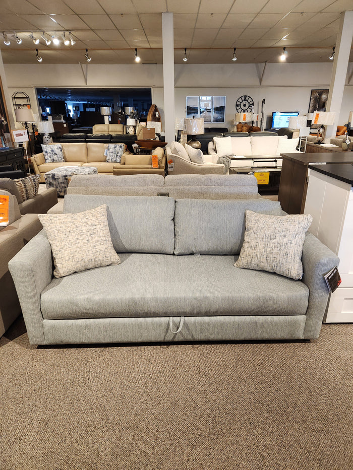 The Decor-rest 2465 Queen Sofabed in light gray, with two patterned cushions and Canadian upholstery, is showroom-displayed.