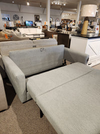 The Decor-rest 2465 Queen Sofabed in gray Canadian upholstery is shown extended in a furniture showroom.