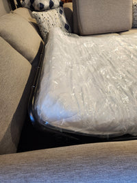 The Superstyle 1014 Trinity Double Sofabed Sectional features a mattress in plastic between beige sofa cushions.