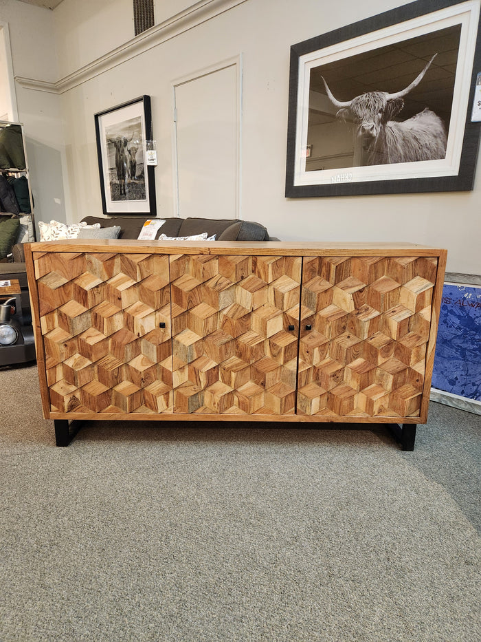 The Jofran Geometrix Accent Cabinet features 3D cube doors and is displayed with framed wall art in a showroom.