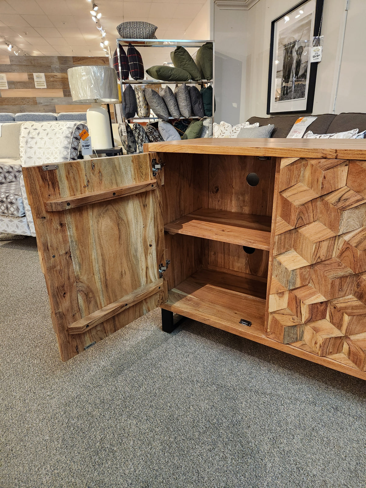 The Geometrix Accent Cabinet by Jofran stands open, revealing shelves and geometric patterns in a decor store.