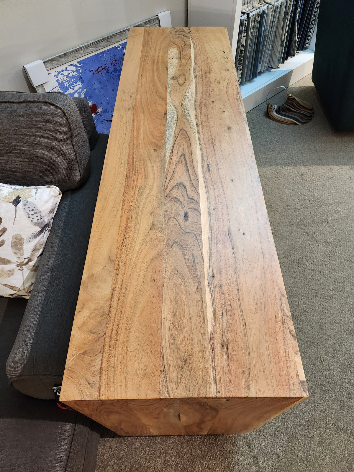 The Jofran Geometrix Accent Cabinet sits beside a gray couch and shelf, paired with a natural wood-grain table.