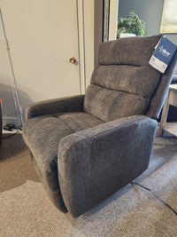 A gray Best 9NP34 Power Space Saver Recliner is on a carpeted floor near a closed door and side table.