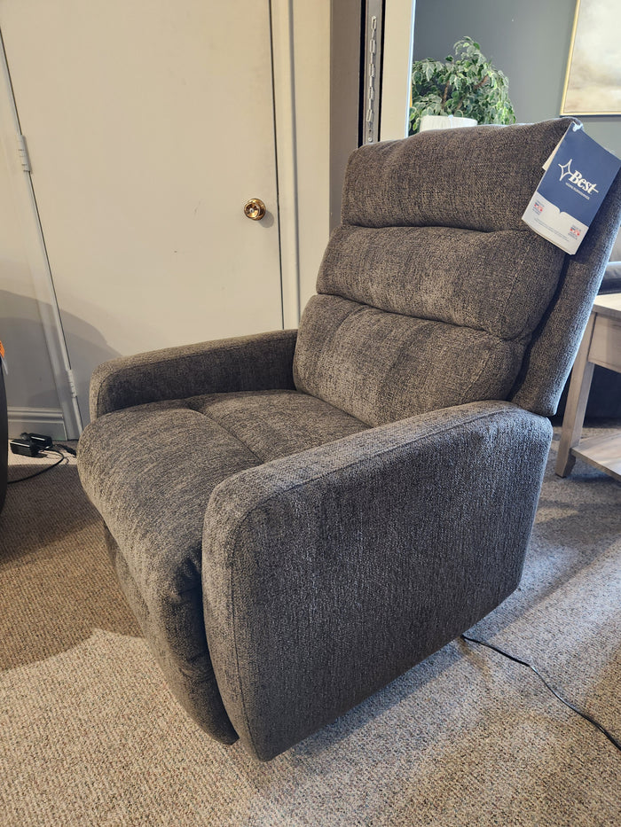 A gray Best 9NP34 Power Space Saver Recliner is on a carpeted floor near a closed door and side table.