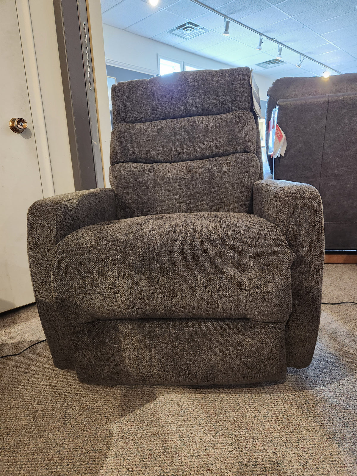 A Best 9NP34 Power Space Saver Recliner sits on a carpeted floor in a well-lit showroom.