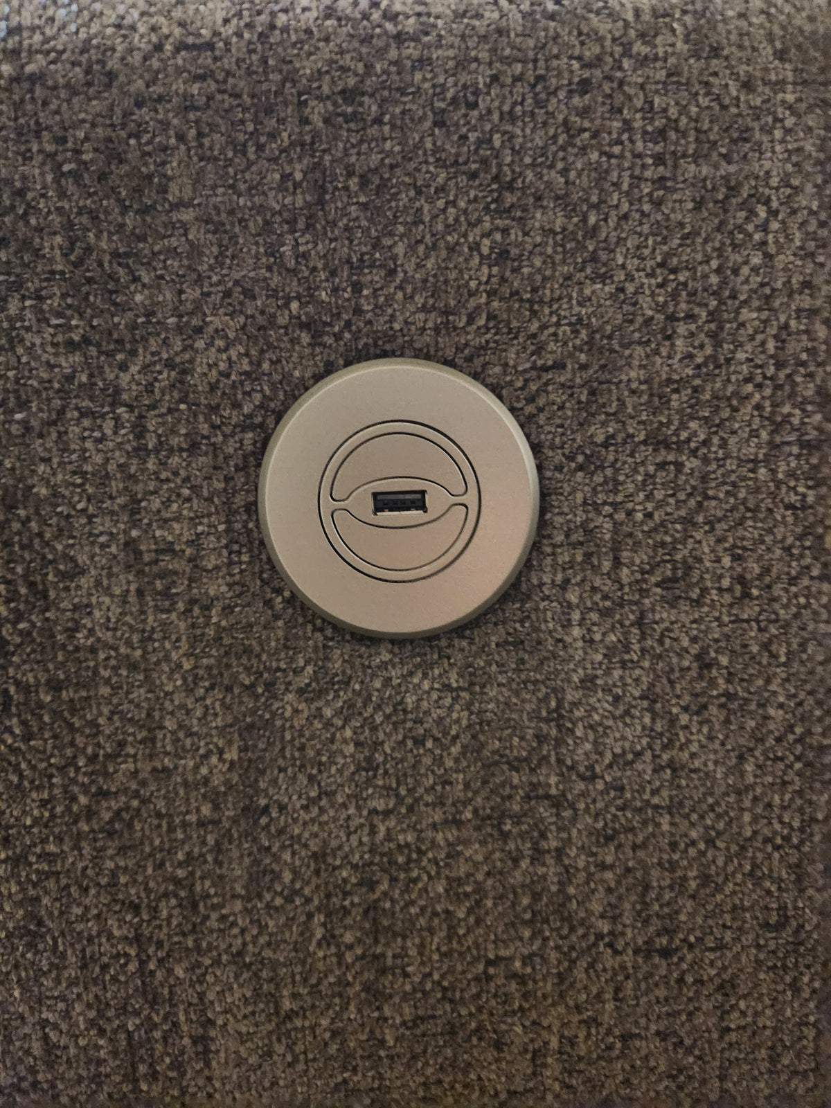 Close-up of the circular USB port on the Best 9NP34 Power Space Saver Recliner with textured gray upholstery.
