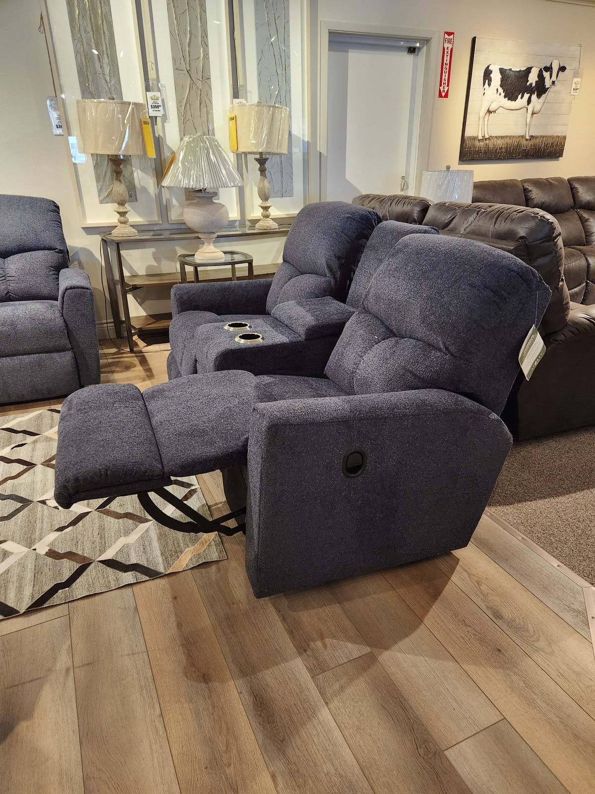 The La-z-boy 780 Hawthorn Reclining Loveseat With Console in gray is shown in a showroom with decor and seating.