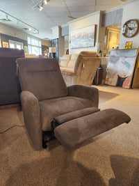The Best 2AP34 Power Space Saver Recliner in gray is showcased in a showroom with art and other seats behind it.