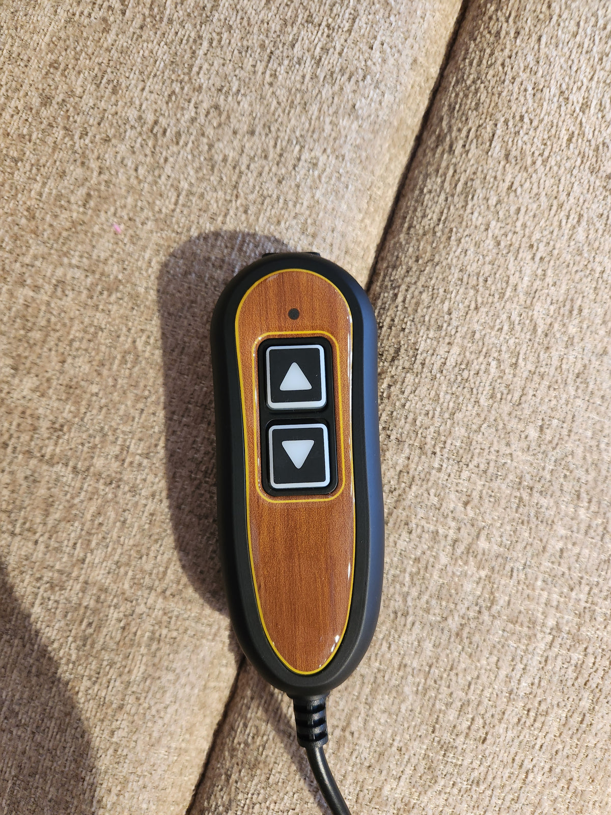 A two-button remote for the Golden Aurora PL480 Power Lift Chair rests on a beige upholstered surface.