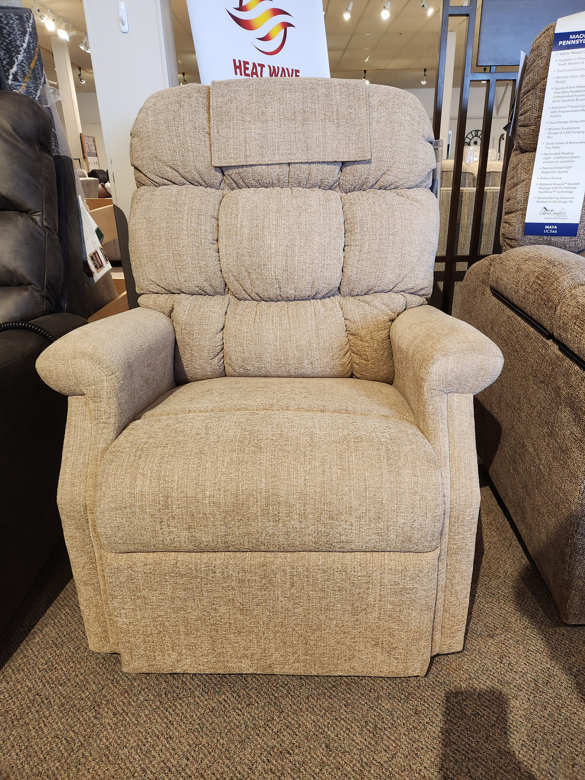 A Golden Aurora PL480 Power Lift Chair in beige is displayed in a showroom with a "Heat Wave" sign behind it.