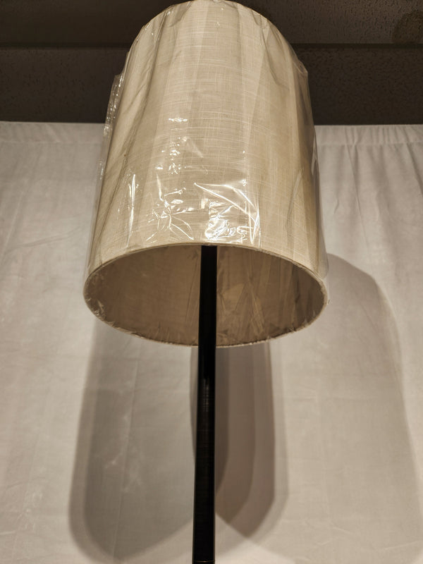 The Adesso Liam Floor Lamp features a beige fabric shade with plastic cover, shown against a white background.