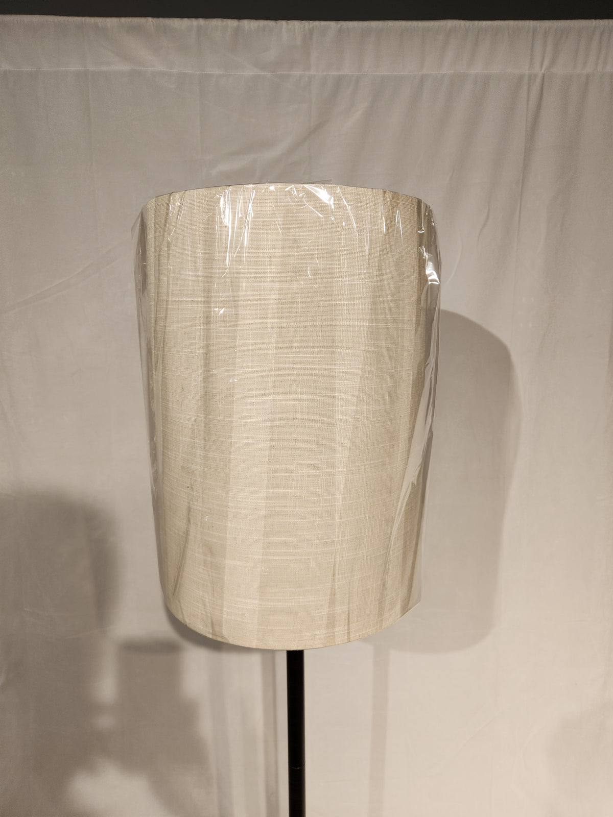 The Adesso Lamp Liam Floor Lamp features a beige plastic fabric shade on a black stand against a white background.