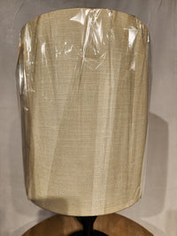 Beige fabric shade on a clear plastic and black wood Adesso Lamp Mayfair Table Lamp, set on a neutral background.
