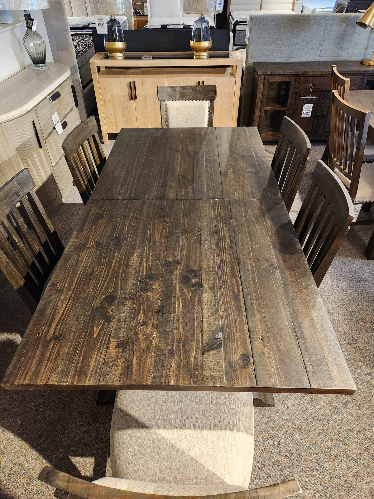 The 2491 Bellamy Dining Package by Magnussen, with six chairs and a bench, is displayed in a furniture showroom.