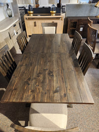 The 2491 Bellamy Dining Package by Magnussen, with six chairs and a bench, is displayed in a furniture showroom.