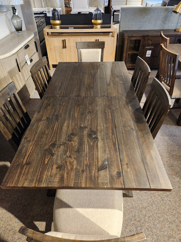 The 2491 Bellamy Dining Package by Magnussen, with six chairs and a bench, is displayed in a furniture showroom.