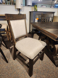 Beige-upholstered wooden dining chair, shown by Magnussen's 2491 Bellamy Dining Package in the showroom.