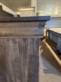 Side view of a Vokes 262-407 Bayshore 7 Drawer Dresser in a showroom with other furniture in the background.