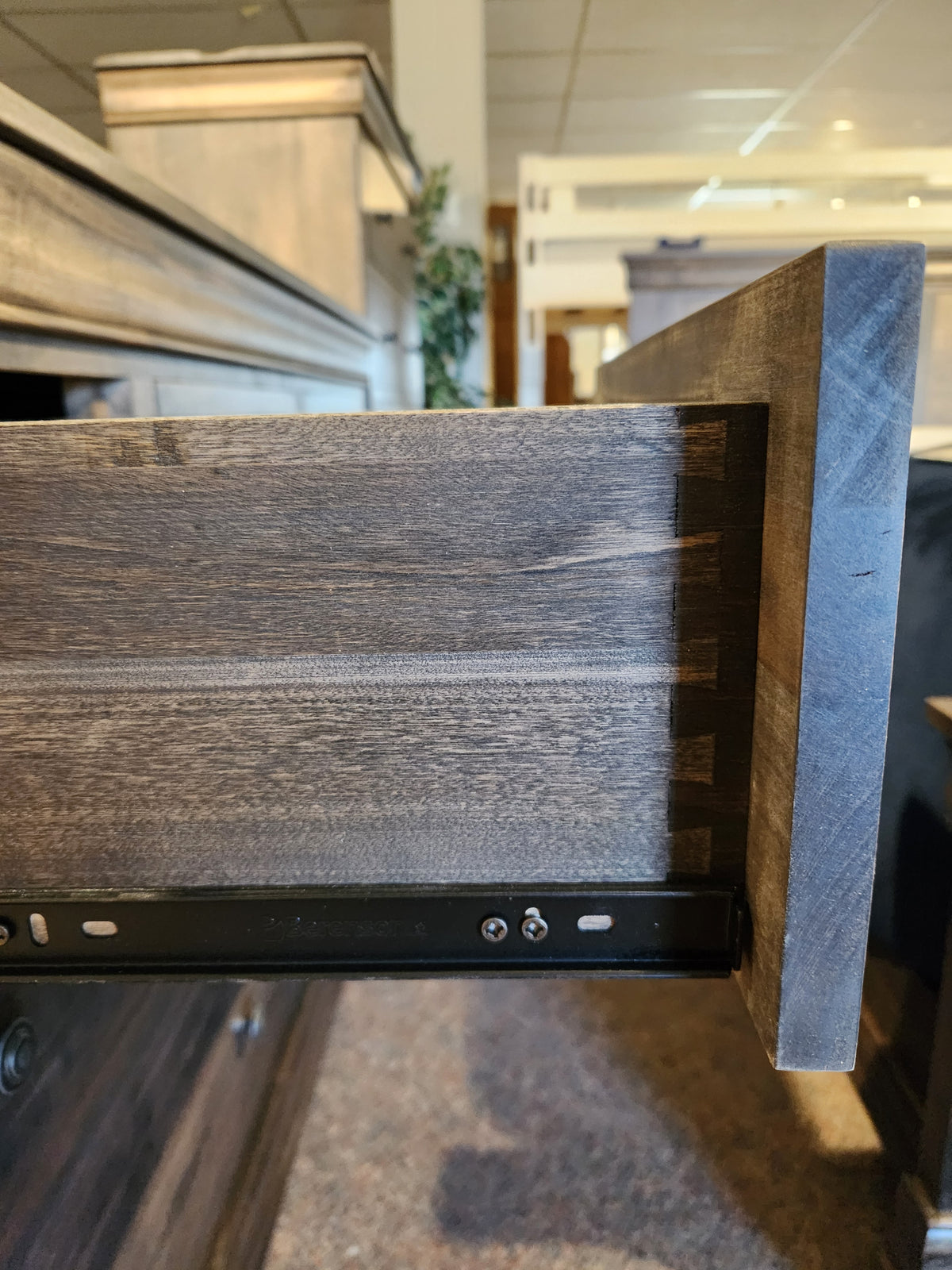 A close-up of a Vokes 262-407 Bayshore 7 Drawer Dresser with dovetail joints, drawers on metal slides in a showroom.