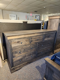The Vokes 262-407 Bayshore 7 Drawer Dresser is displayed in a carpeted furniture showroom.