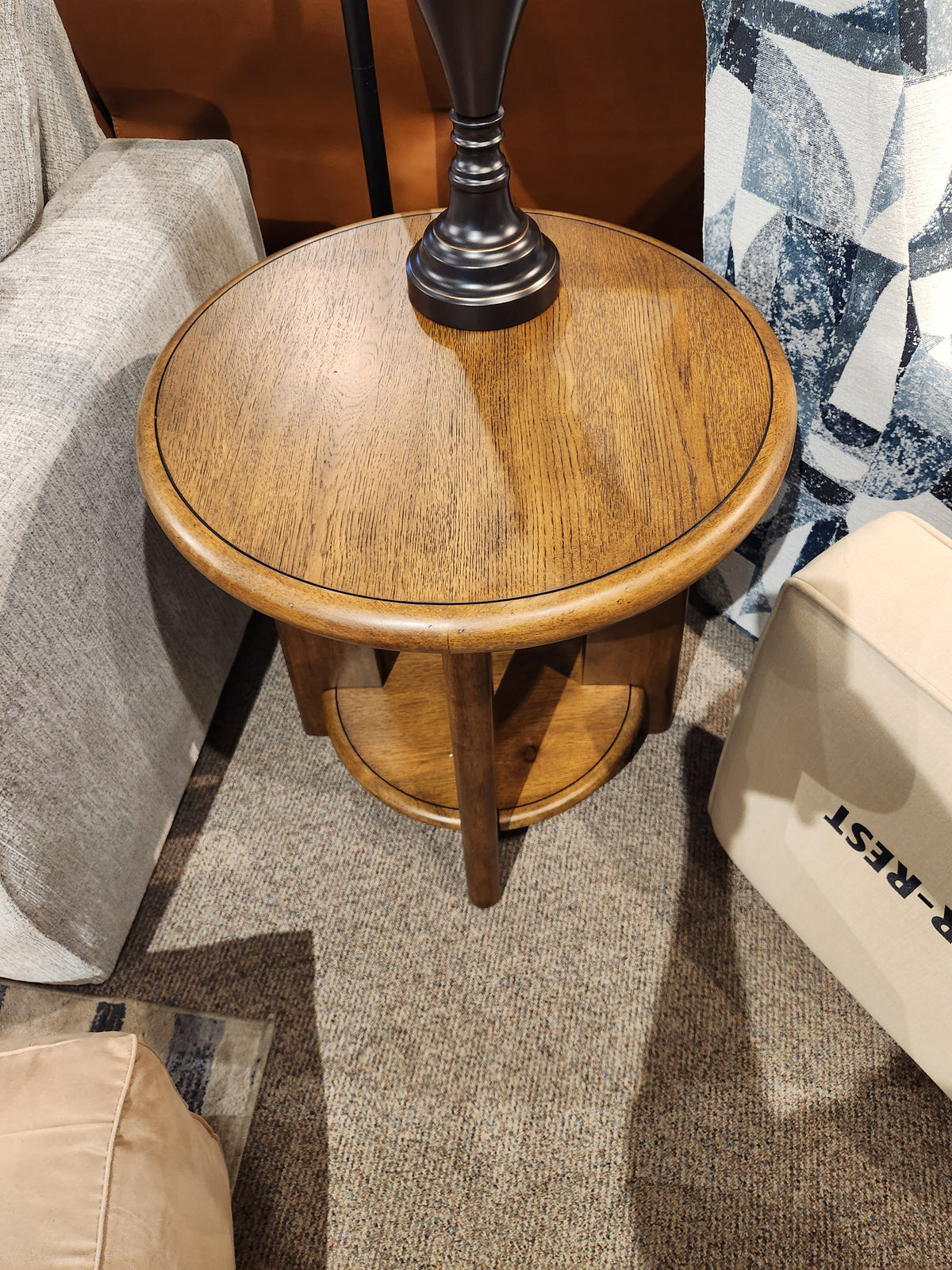 The Magnussen T6354 Tanner Round End Table in tawny brown adds California Casual style with its lower shelf design.