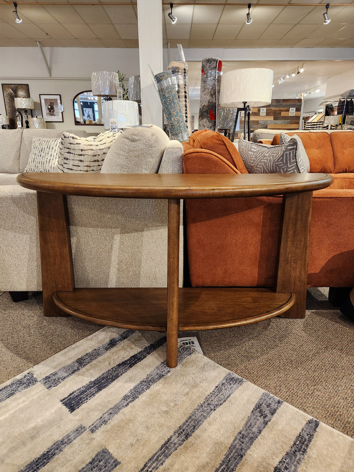 The Magnussen T6354 Tanner Demilune Sofa Table in Tawny Brown adds California Casual style behind two sofas.