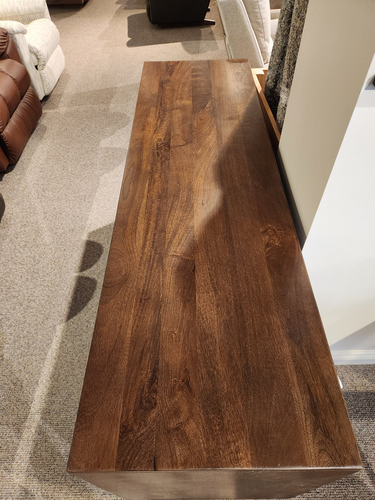 The Jofran Trent Woven Front Accent Cabinet 60" stands on a carpet, surrounded by upholstered furniture.