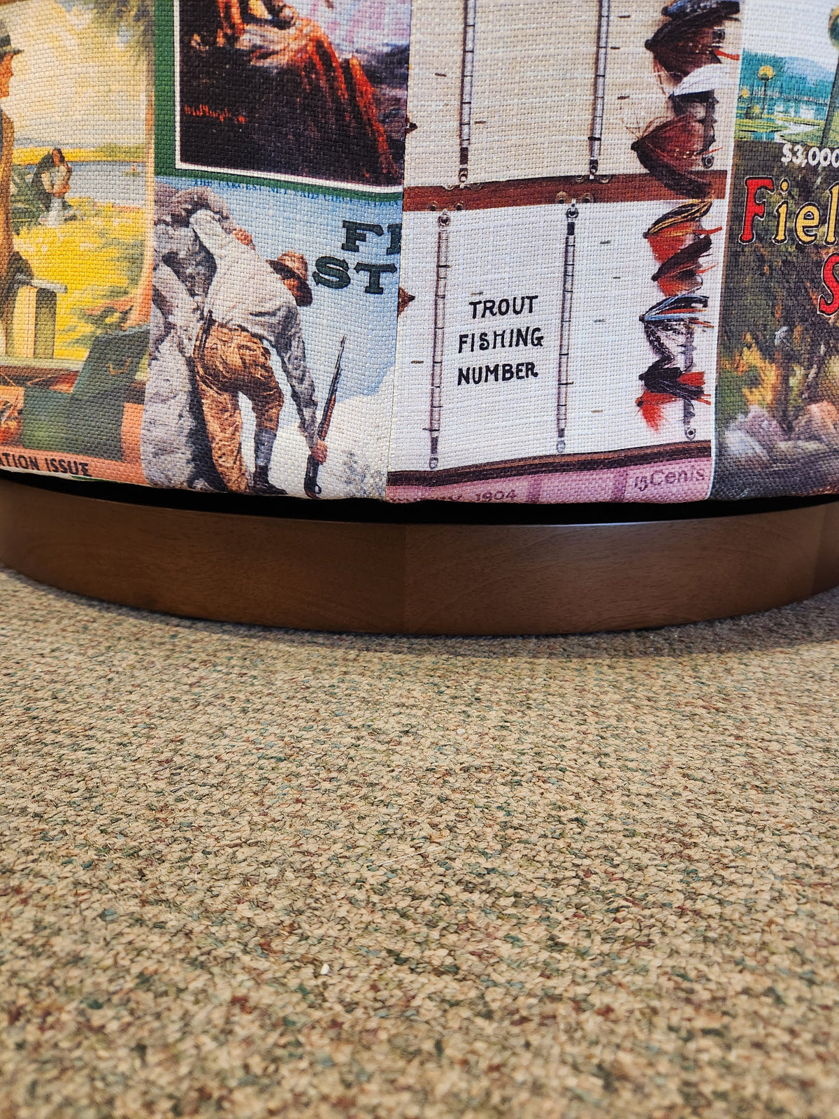 A close-up of the Best Field & Stream April FS2 Swivel Chair on brown carpet with vintage fishing posters.