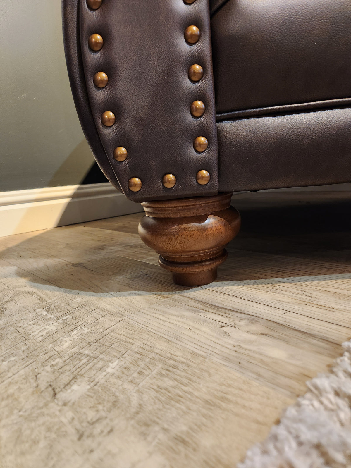 Close-up of the Best Field & Stream Noble Chair corner with brass studs, wood leg, and modern lodge-style details.