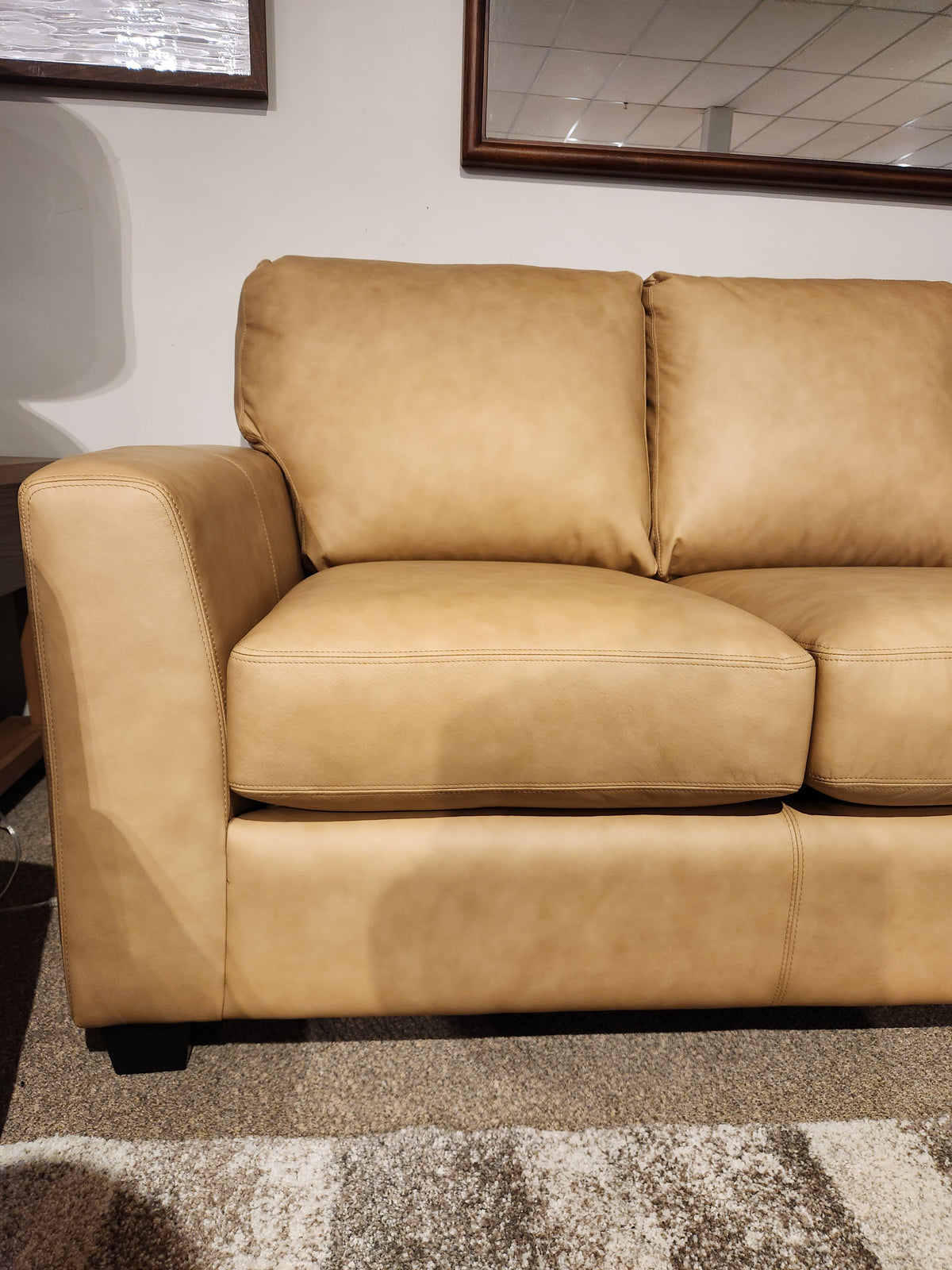 Tan leather Decor-rest 3968 Sofa with deep seats, two cushions, and Canadian upholstery sits below framed wall art.